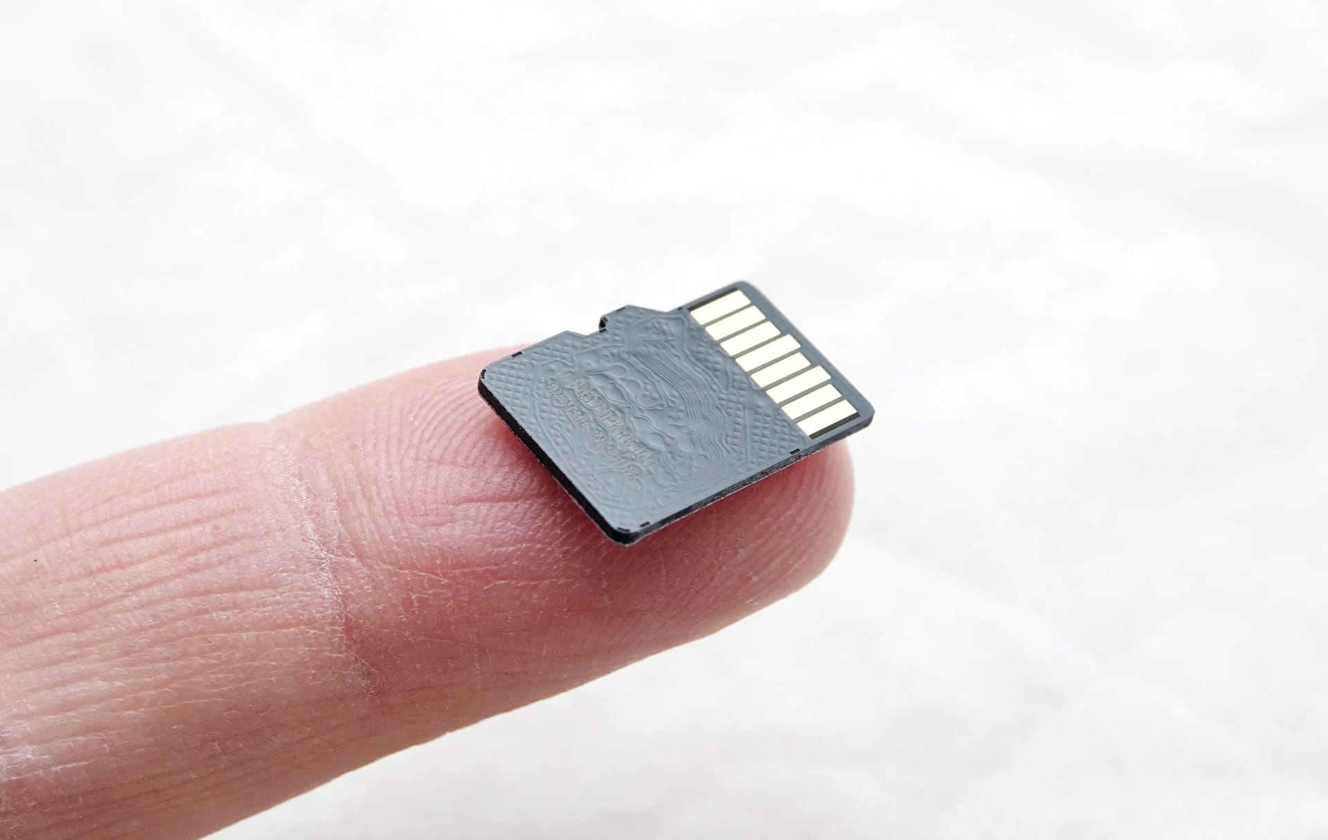 A tiny microSD card on the tip of a finger