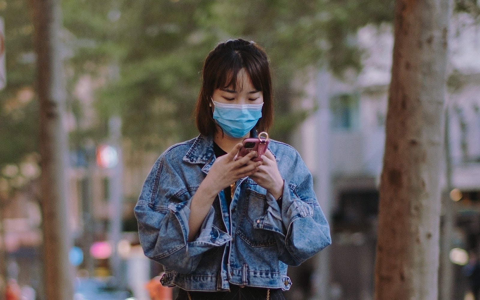 A woman in a face mask uses their phone (Image by Kate Trifo)