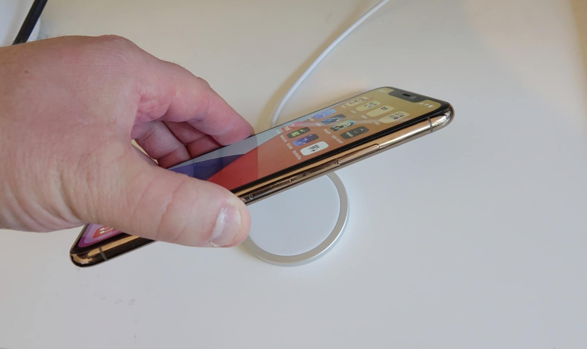 You can charge an iPhone 11 Pro Max on a MagSafe charger, but it won't cling to the back.