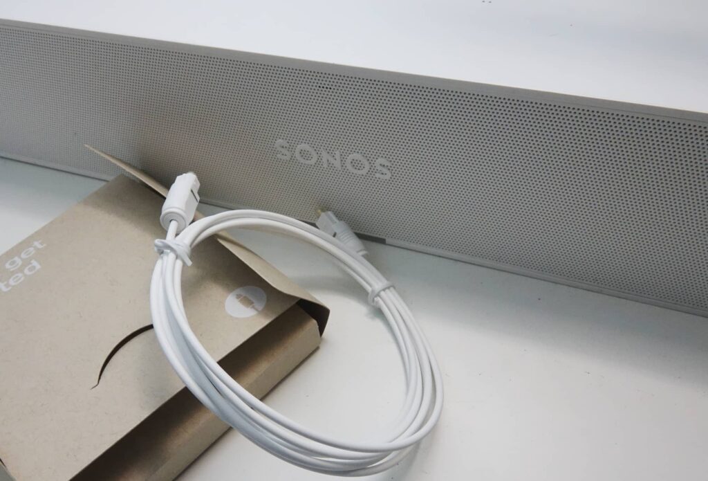 The white Sonos Ray with a white optical cable